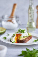 Healthy breakfast: poached egg sandwich, avocado, whole grain bread. Bruschetta on a light background. The keto diet