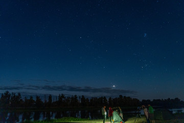 Nigth sky and people standing near tent and telescope