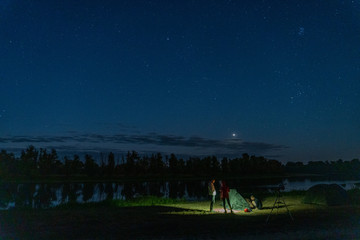 Nigth sky and people standing near tent and telescope