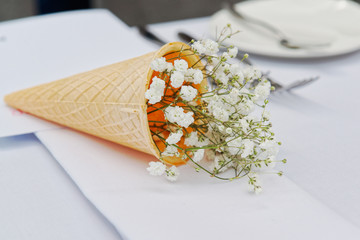 Delicate white Gypsophila flowers in ice cream cone. The wedding decor. Table set for an event party or wedding reception. Beautiful flowers on table.