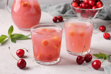 Kissel with sweet cherries in two glasses and jug on gray background, Horizontal format, Closeup