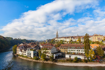 Fototapeta na wymiar Stunning panorama view of Bern old town with Bern Minster (Münster)cathedral and Aare river flowing around, on sunny autumn day with blue sky and cloud, Switzerland