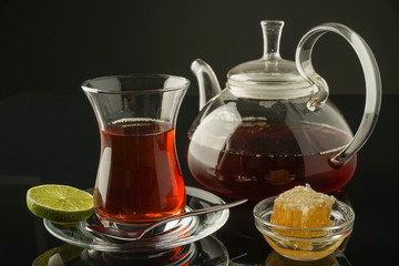 Turkish style black tea with lime with honey in combs on a dark background.