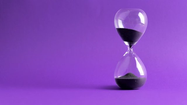 4K Hourglass Black Sand Flowing on purple Screen Background