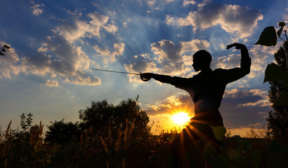 Silhouette of a man with a saber against the background of sunrise or sunset. Freedom fight...
