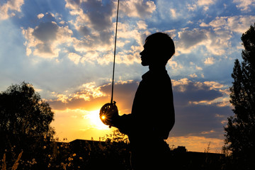 Silhouette of a man with a saber against the background of sunrise or sunset. Freedom fight concept. Outdoor fencing training.