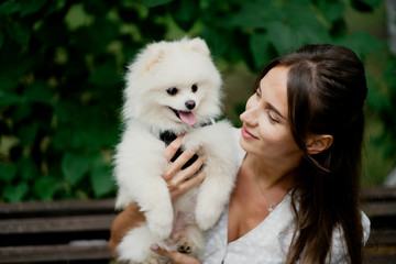 young woman holding a white puppy
