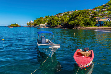 A view past boats moored on a jetty along the beach at Barrouallie, Saint Vincent