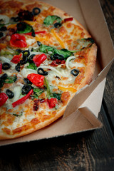 Delicious fresh pizza served on wooden table background. Summer dinner or lunch. Freshly baked Italian vegetarian pizza with vegetables. Top view.