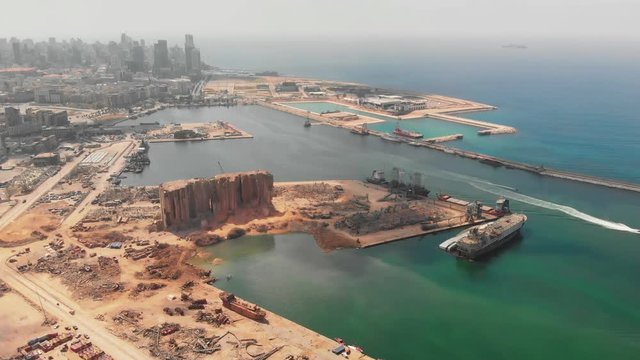 Aftermath of the Beirut port explosion, featuring a damaged grain silo, twisted metal structures, and scattered debris amid ongoing reconstruction efforts.	