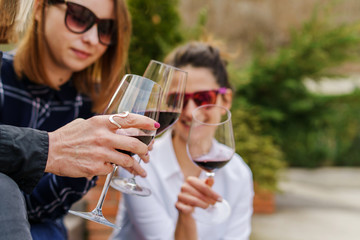 Close up on hands with glasses of red wine celebrating toasting - Female friends cheers with alcohol drink outdoor in day