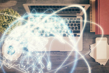 Business theme hologram drawings over computer on the desktop background. Top view. Multi exposure. Concept of international connections.