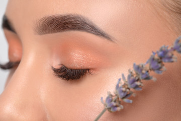 Eyes and eyebrows close-up.Portrait of a beautiful teenage girl with beautiful makeup, extended long eyelashes and healthy clean skin.Near the eyes is branch of lavender.Makeup and cosmetology concept