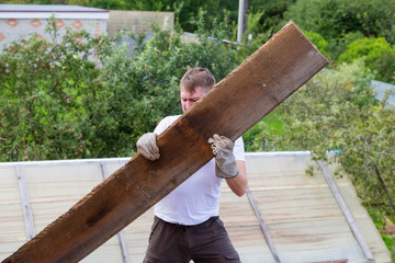 dismantling the roof. The worker removes old boards