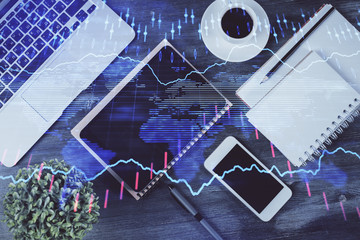 Double exposure of forex chart hologram over desktop with phone. Top view. Mobile trade platform concept.