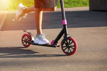 sneakers on female legs close up. woman riding on scooter