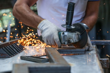 the hands of the master saw the metal with a grinder. metal works in the workshop close up. 