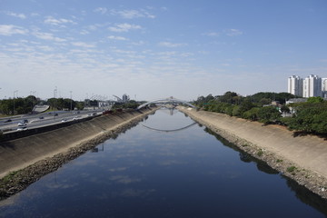 dark waters of Tiete river reflecting the sky and bridge. Sao Paulo, Brazil