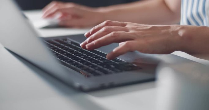 Close up of female hands typing on wireless laptop. Woman sitting at table and using computer. Concept of people and technology.
