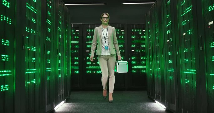 View from below on Caucasian beautiful woman technician carrying tools box and walking among servers and big data processors. Female engineer in data storage working in digital security department.