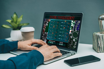 Man playing poker online, making bets using his laptop