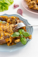 Homemade guinea fowl stew with gravy and vegetables on a plate. Vertical