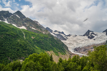 Beautiful landscape of glacier in summer season. Glacier mountain with green vegetation on high ground in cloudy weather.
