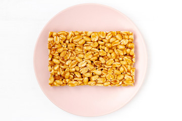 A Bar of peanut brittle on the plate. Food energy mockup. Background image for sweet snacks. Top view, flat lay, copy space.