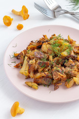 Fried chanterelle mushrooms (Cantharellus cibarius) with potatoes on a plate.