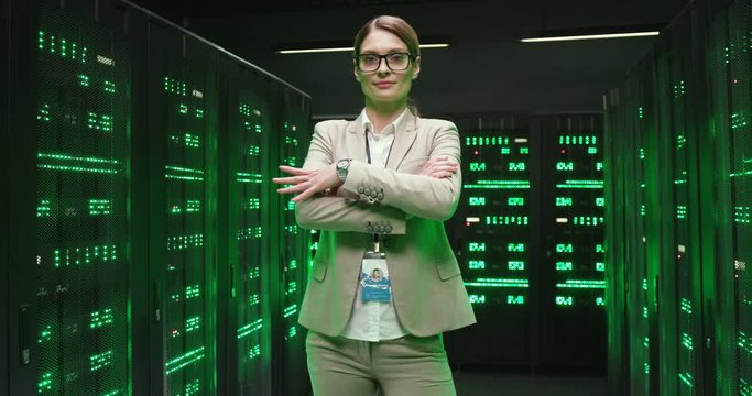 Portrait of young happy Caucasian beautiful woman, worker of database storage smiling while standing with crossed hands. Female good-looking cheerful smiled engineer or analytic in datacenter.