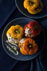 Colorful baked bell peppers stuffed with mince and rice on blue background