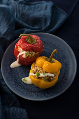 Colorful baked bell peppers stuffed with mince and rice on blue background