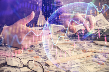 Double exposure of man's hands holding and using a digital device and forex graph drawing. Financial market concept.