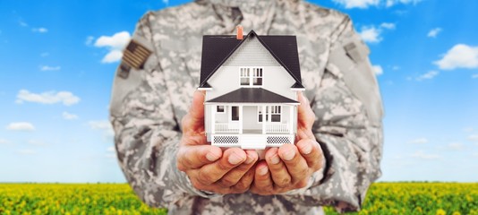 Naklejka premium Soldier man holding a model of the house