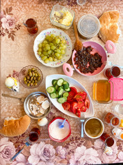 Fototapeta na wymiar Delicious Turkish Traditional Breakfast serving on table ingredients with Egg, Butter, Olives, Fresh Vegetables, Various Cheese, Bread Pisi, Patty and Black Tea.