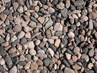 Textured background of natural stones. Small colorful stones bathed in sunlight background.