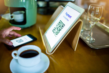 Selective focus to customer using smart phone scan QR code on tablet to payment at counter bar in coffee shop. Accepted generate digital pay without money.
