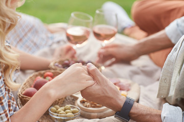 Close up of loving couple holding hands while enjoying picnic outdoors during romantic date, copy space