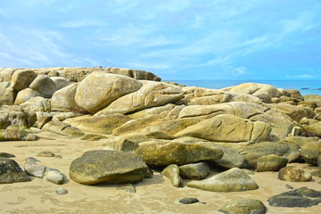 On the seashore there are many large rocks piled together.	