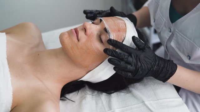 Beautiful young woman at the reception of the beautician, the skin of the face is covered with a cosmological film. Cosmetic procedure in a modern beauty salon. personal care