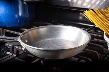 Preparing Spaghetti Carbonara on a black stove with an aluminum pan