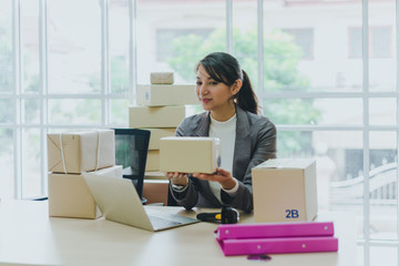 A beautiful businesswoman working at home is checking orders for products to be delivered to her customers from notebooks.