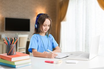 Little girl learning for school desk with headphones