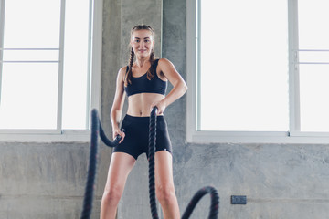 Obraz premium Young female athletes exercise in the gym using ropes. She's wearing a sports wear to exercise.