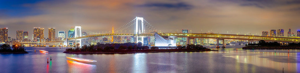 Tokyo Destinations. View of Renowned Rainbow Bridge in Odaiba Island in Tokyo At Twilight with Line of Skyscrapers Behind