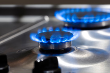 Gas Oven Concepts. Macro Shoot of Two Gas Burners on Stove Surface with Flames and Two Knobs in...