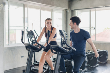 Male and female athletes talk about exercise, cycling in the gym. They wear sportswear to exercise.