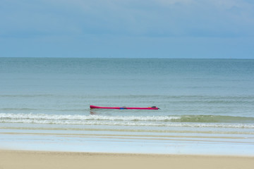 
On the beach a man rowing on the sea.
