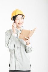 スマートフォンで通話する作業服姿の女性