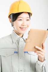 スケジュール帳を持った作業服を着た女性